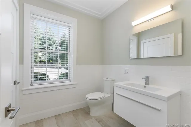 a bathroom with a toilet a sink a mirror and a window