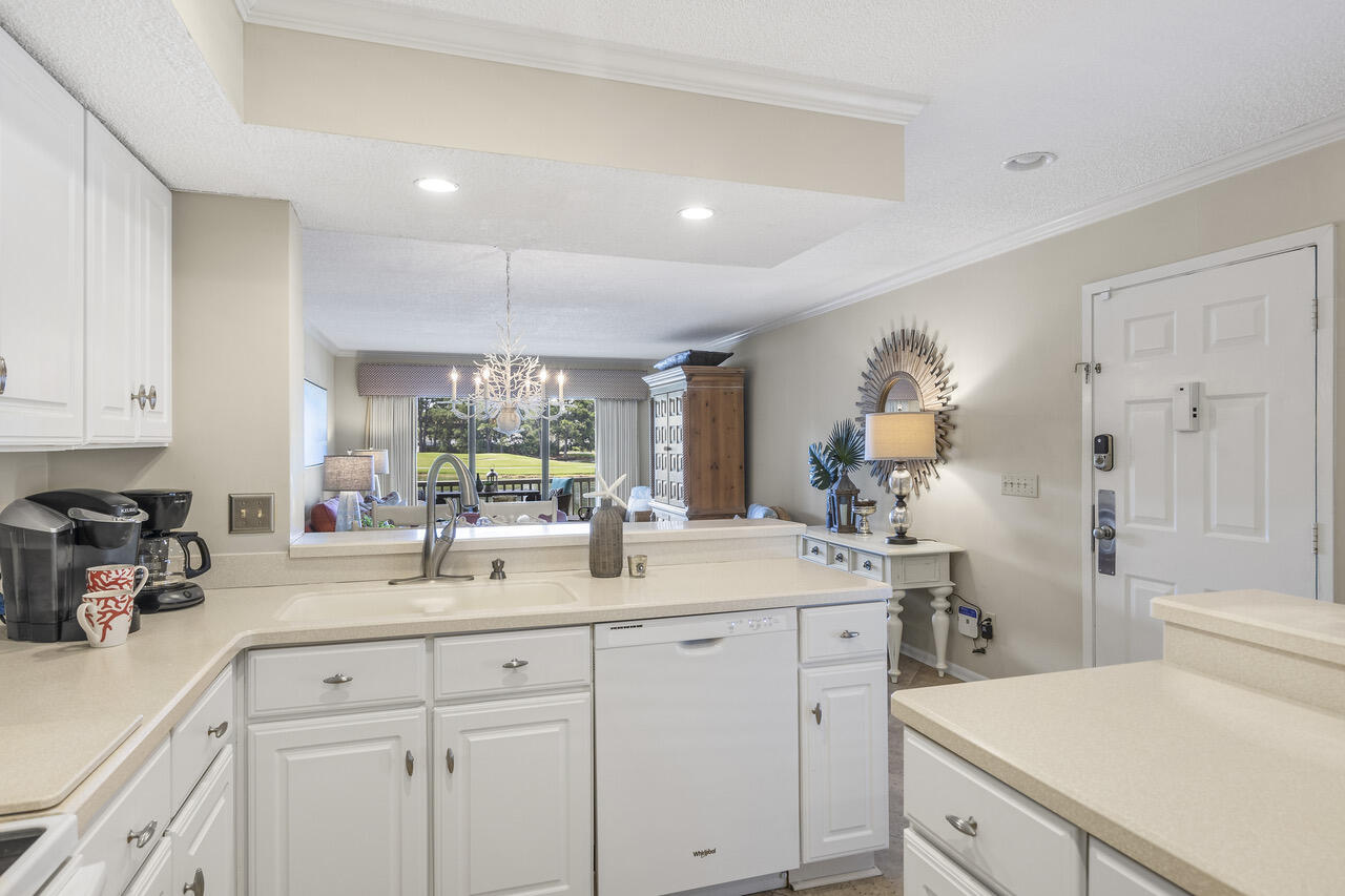 906 Harbour Point Lane, Unit 906 Miramar Beach, FL 32550 - Photo 11 of 36 a kitchen with a sink dishwasher and white cabinets with wooden floor