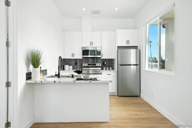 a kitchen with stainless steel appliances a refrigerator a stove a sink and a potted plant