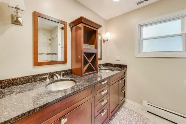 a en suite bathroom with a granite countertop sink and a mirror