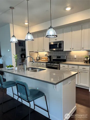 a kitchen with stainless steel appliances a table a sink and cabinets