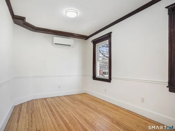 a view of an empty room with wooden floor and a window