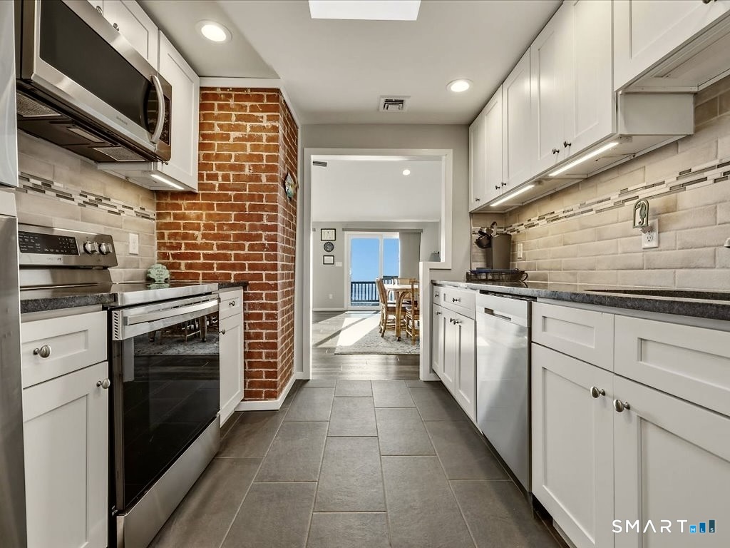75 Shore Road Clinton, CT 06413 - Photo 17 of 40 a kitchen with stainless steel appliances a stove sink microwave and cabinets