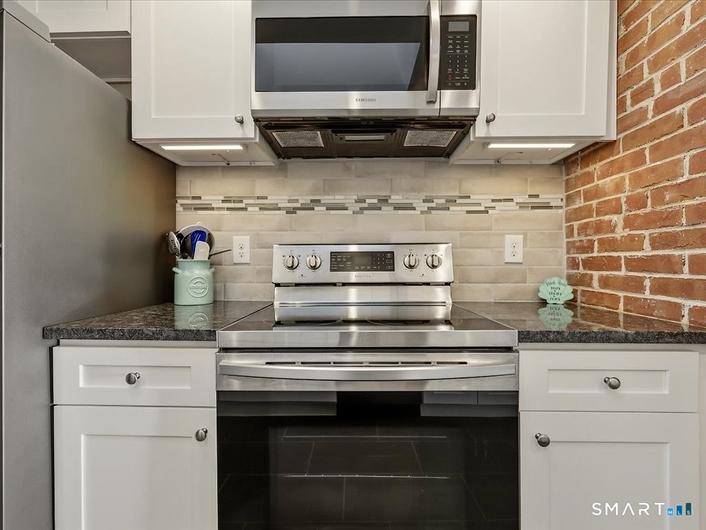 75 Shore Road Clinton, CT 06413 - Photo 19 of 40 a kitchen with stainless steel appliances granite countertop a stove and a microwave