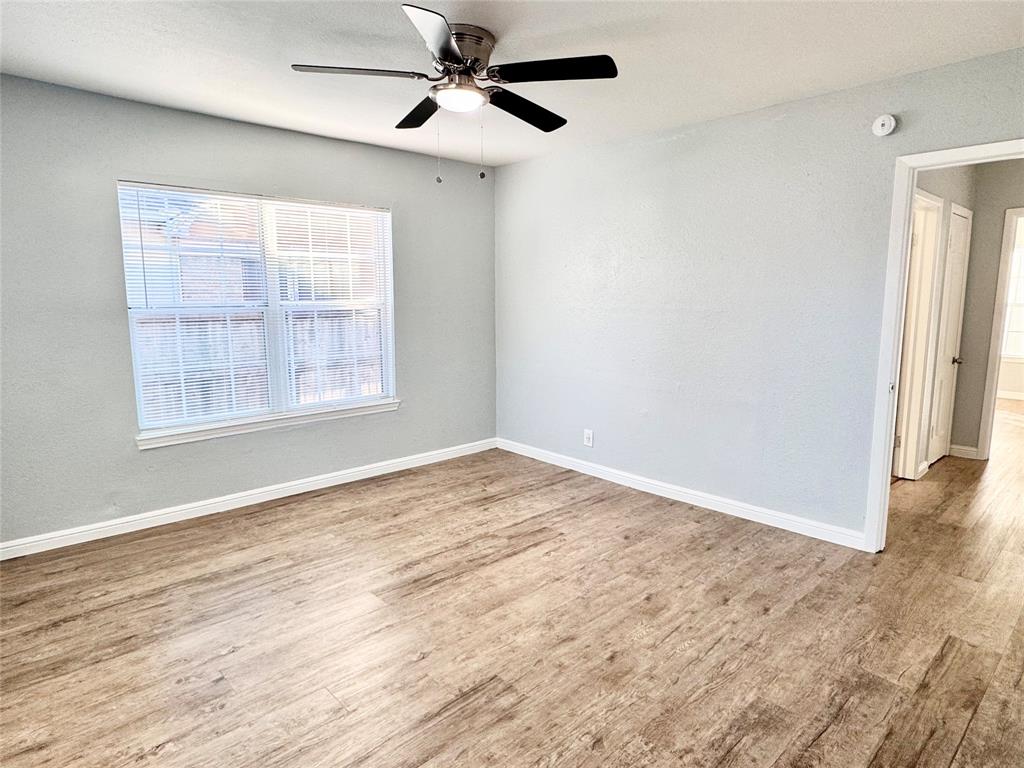 202 North Riverside Drive Fort Worth, TX 76111 - Photo 12 of 25 an empty room with wooden floor ceiling fan and windows