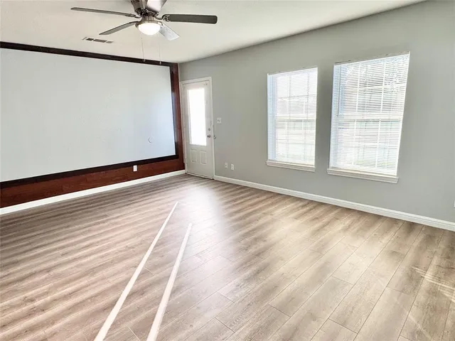 a view of an empty room with a window and wooden floor