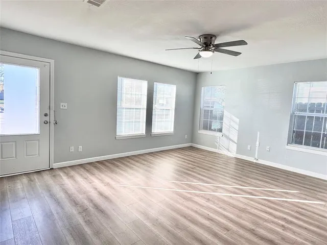 a view of an empty room with a window and wooden floor