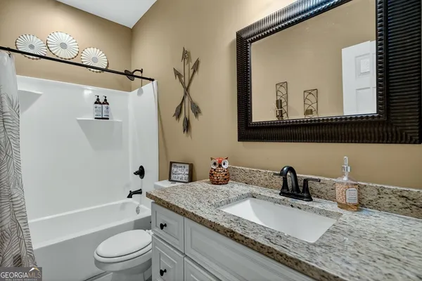 a bathroom with a granite countertop toilet a sink and a mirror