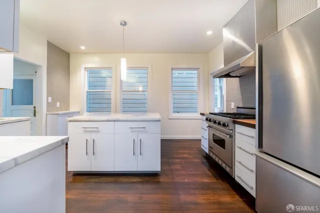 a kitchen with granite countertop a stove a sink and a refrigerator
