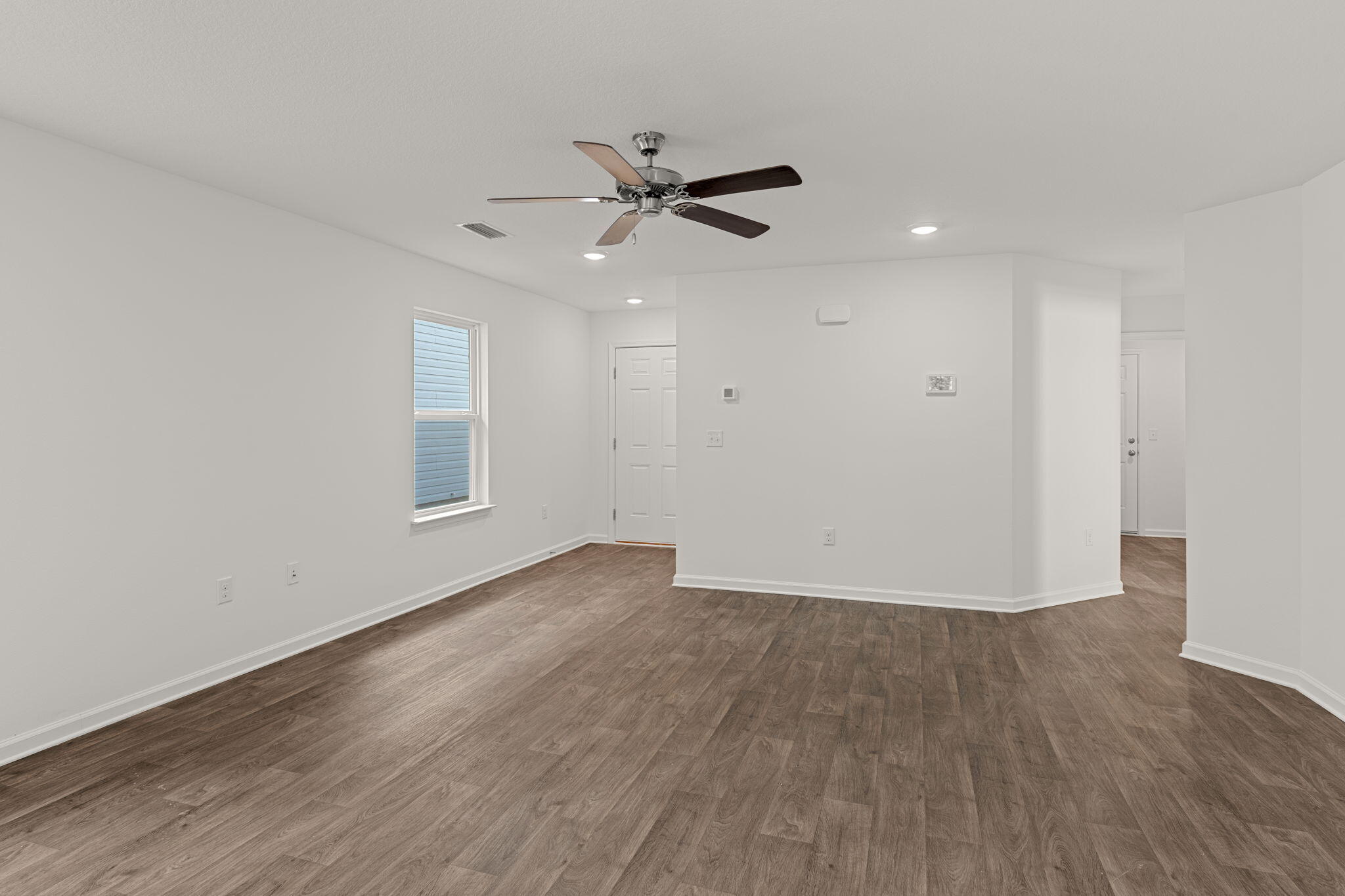 545 Earl Godwin Road Freeport, FL 32439 - Photo 8 of 50 an empty room with wooden floor a ceiling fan and windows