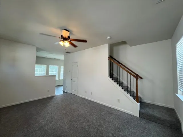 a view of an empty room with wooden floor and a ceiling fan