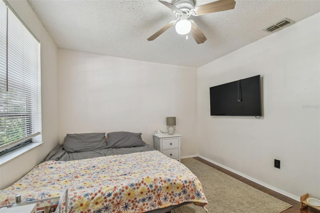 134 Sycamore Lane, Unit H Oldsmar, FL 34677 - Photo 27 of 44 a bedroom with a large bed and a flat tv screen on dresser