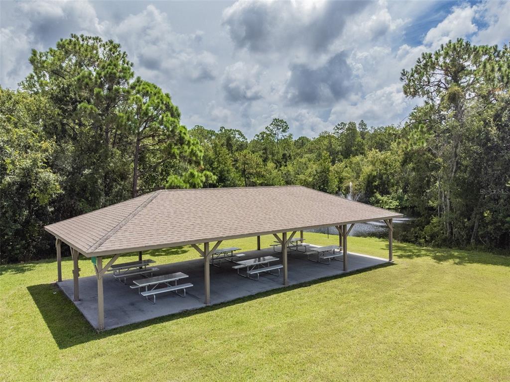 134 Sycamore Lane, Unit H Oldsmar, FL 34677 - Photo 38 of 44 a view of a patio with table and chairs under an umbrella with large trees