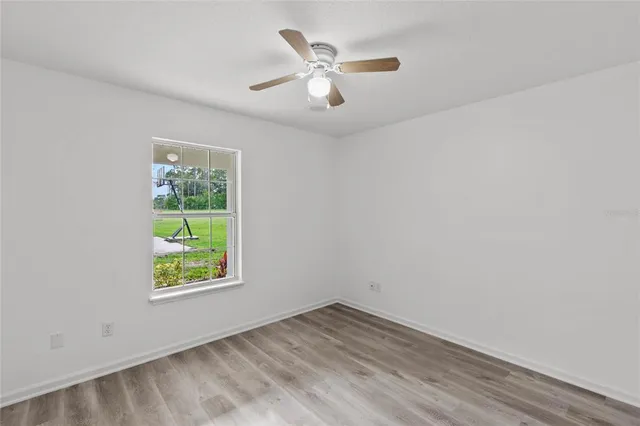 an empty room with a window and a ceiling fan