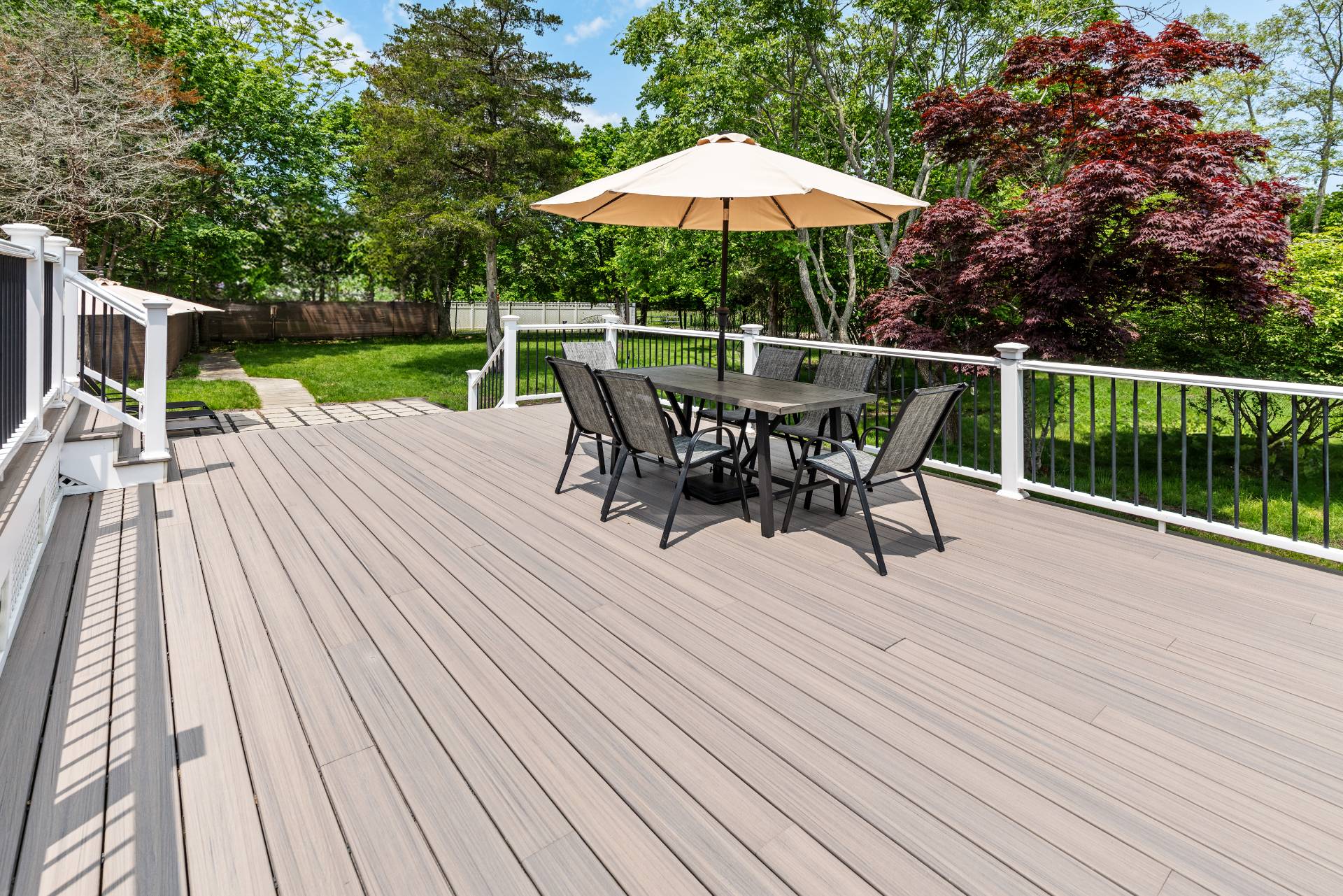 43 Shinnecock Road Hampton Bays, NY 11946 - Photo 4 of 17 a view of a roof deck with table and chairs under an umbrella with wooden floor and fence