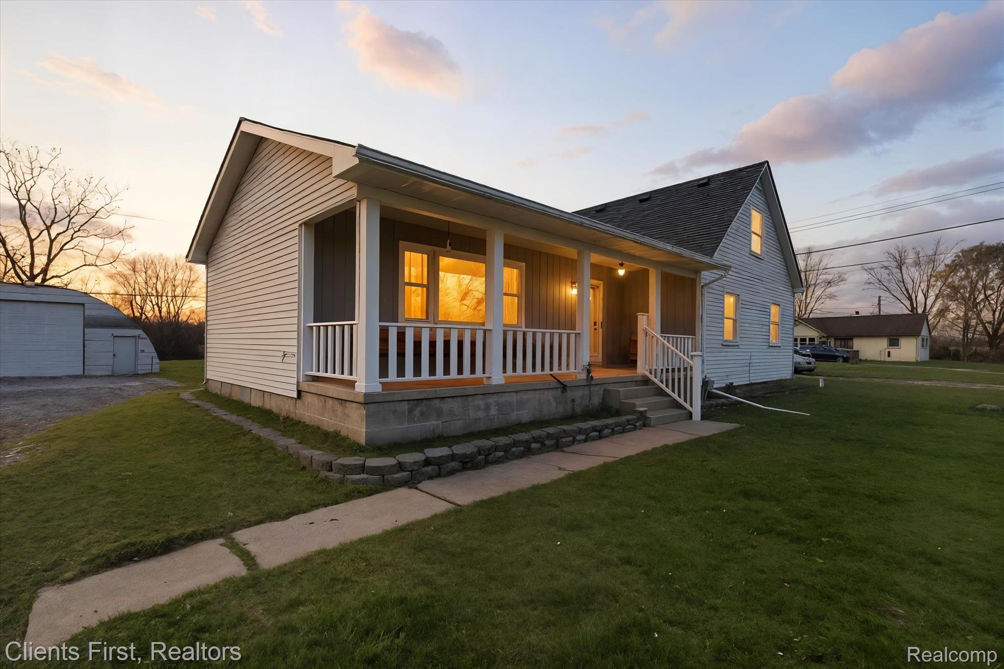 Bungalow with a yard, a porch, a shingled roof, and an outbuilding