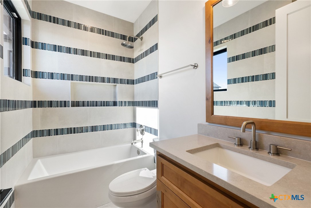175 Pointview Drive Marble Falls, TX 78654 - Photo 29 of 34 a bathroom with a granite countertop sink toilet a mirror and bathtub
