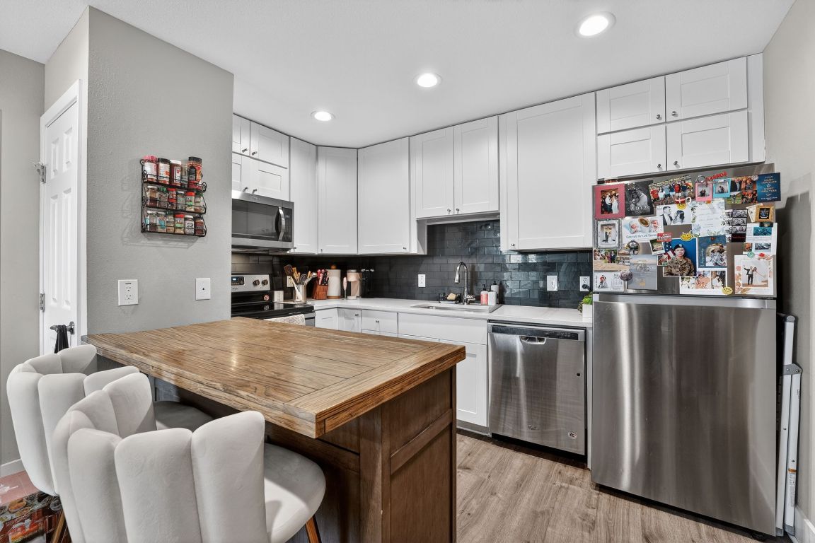 935 La Posada Drive, Unit 128 Austin, TX 78752 - Photo 5 of 18 a kitchen with stainless steel appliances granite countertop a table chairs sink and refrigerator