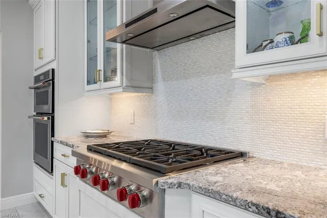 a kitchen with stainless steel appliances a white table chairs and a refrigerator