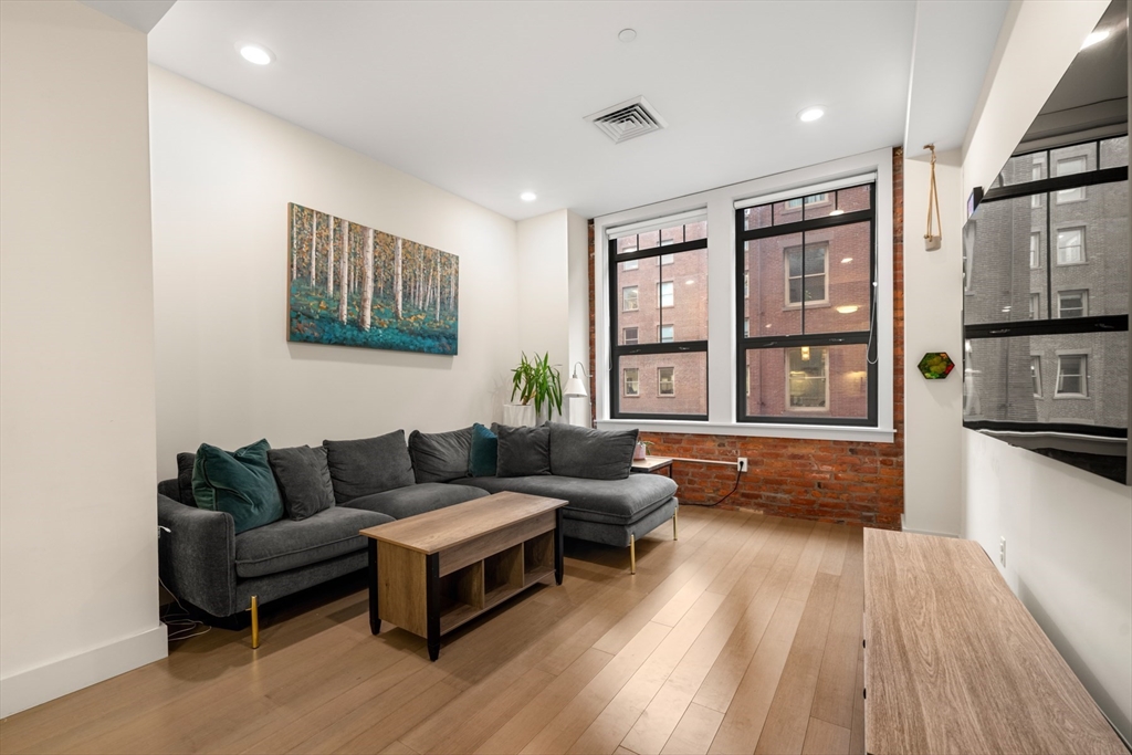 121-127 Portland Street, Unit 307 Boston, MA 02114 - Photo 6 of 27 a living room with furniture and a wooden floor