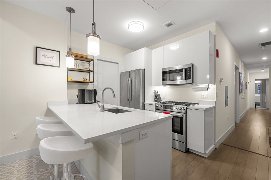 121-127 Portland Street, Unit 307 Boston, MA 02114 - Photo 8 of 27 a kitchen that has a kitchen island a stove a table and chairs in it