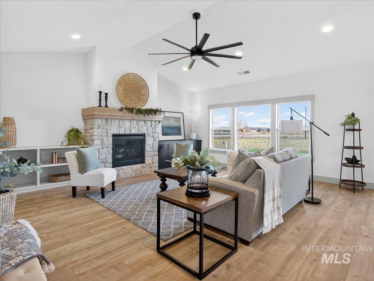 2240 Little Rock Road Emmett, ID 83617 - Photo 12 of 50 Living area with a stone fireplace, lofted ceiling, light wood-style flooring, a ceiling fan, and recessed lighting