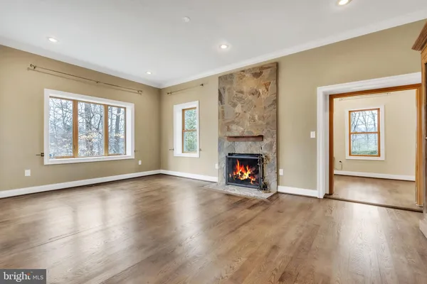 an empty room with windows a fireplace and wooden floor