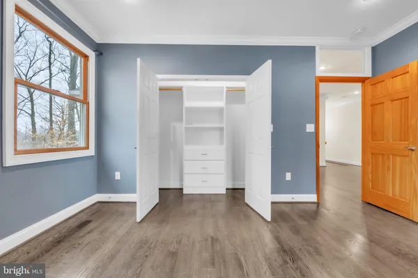 an empty room with wooden floor closet and windows