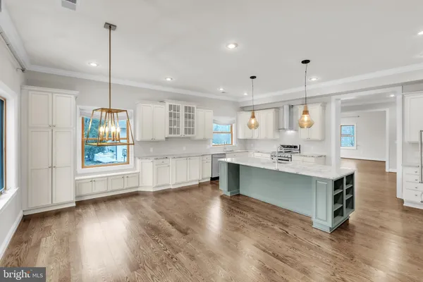 a kitchen with kitchen island a sink dishwasher stove and white cabinets with wooden floor