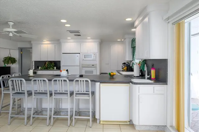 a kitchen with stainless steel appliances kitchen island granite countertop a table chairs refrigerator and sink
