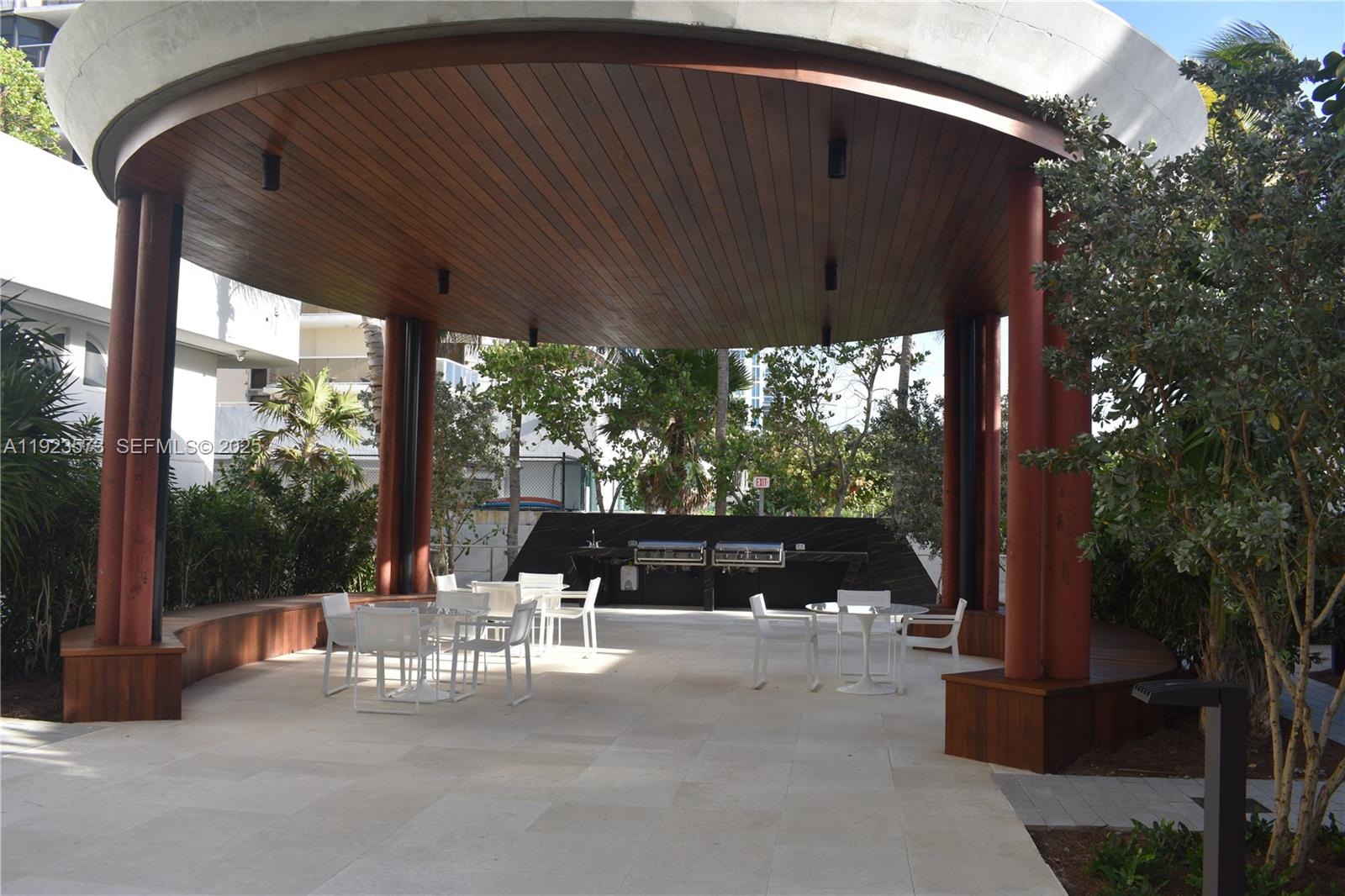 6365 Collins Avenue, Unit 3804 Miami Beach, FL 33141 - Photo 8 of 33 a view of a patio with a table chairs and a floor to ceiling window