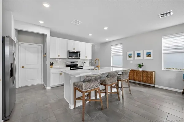 a kitchen with kitchen island granite countertop wooden floors and white cabinets