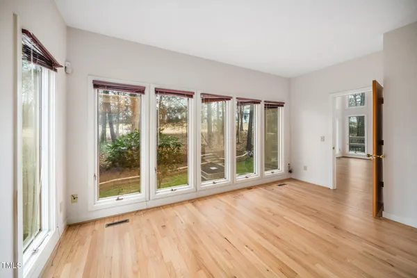 a view of an empty room with wooden floor and a window