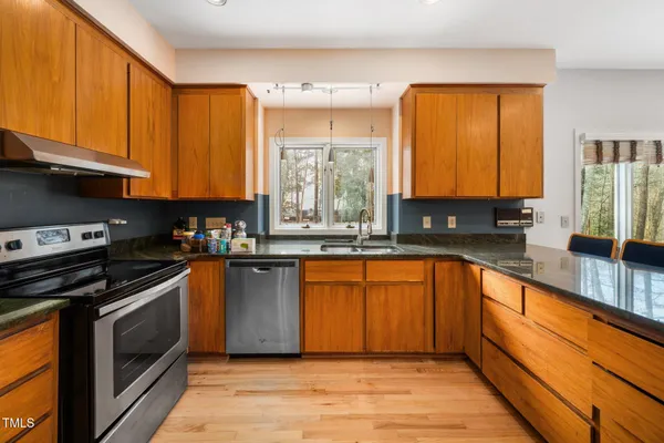 a kitchen with stainless steel appliances granite countertop a stove a sink and a microwave