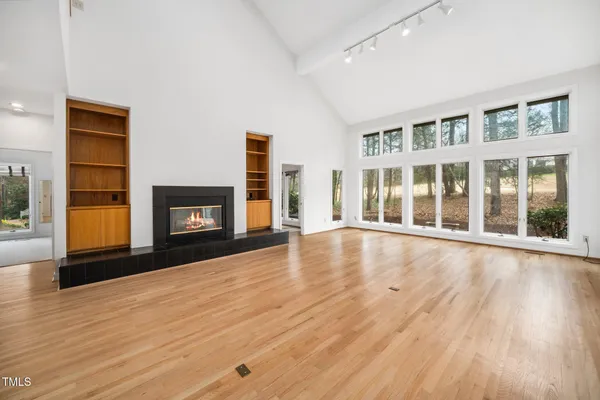 a view of an empty room with wooden floor fireplace and a window