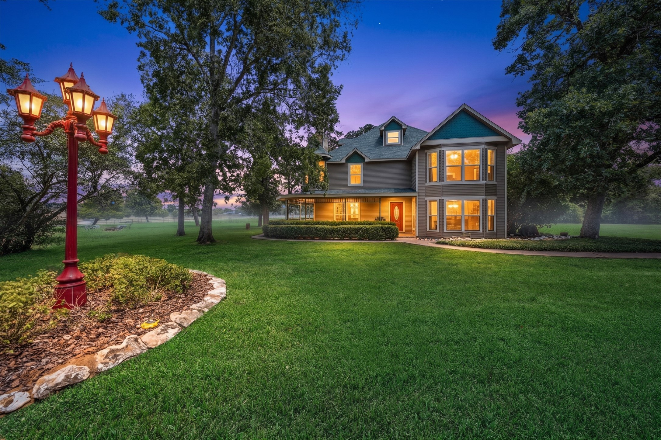 25948 Nelson Road Hempstead, TX 77445 - Photo 1 of 46 Beautiful dusk exterior view highlighting the stately residence, warm exterior lighting, expansive front lawn, mature trees, and landscaped grounds.