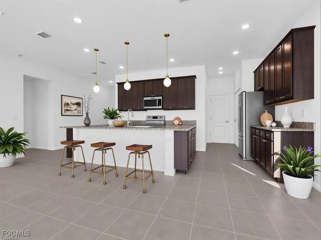a open kitchen with stainless steel appliances kitchen island granite countertop a sink a stove a microwave a dining table and chairs with wooden floor