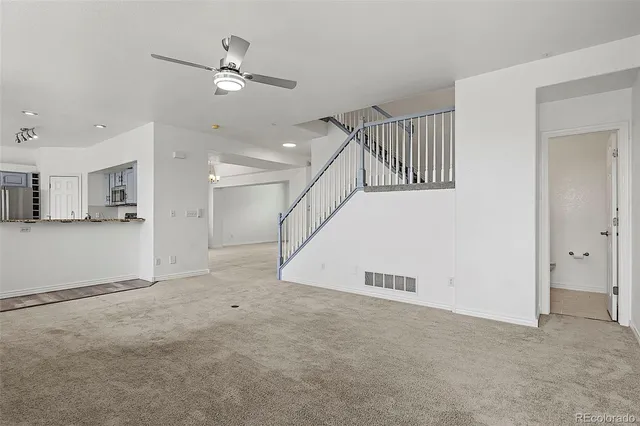 a view of an empty room with kitchen view and a window