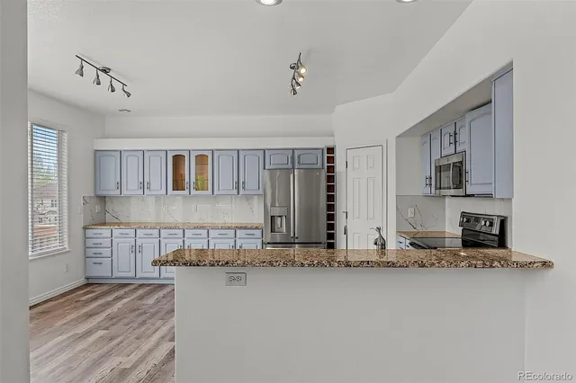 a view of a kitchen with granite countertop a sink and dishwasher a stove top oven with wooden floor