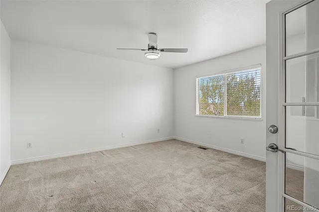 an empty room with a window and ceiling fan