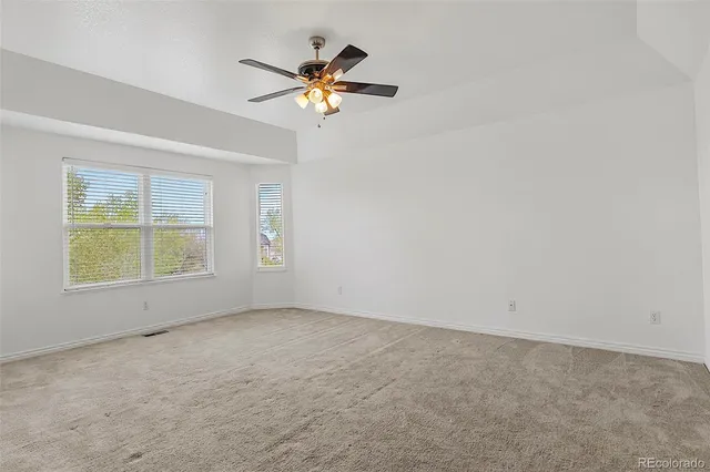 an empty room with a chandelier fan and windows