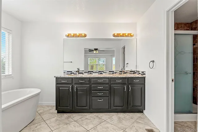 a spacious bathroom with a granite countertop sink a mirror and a bathtub