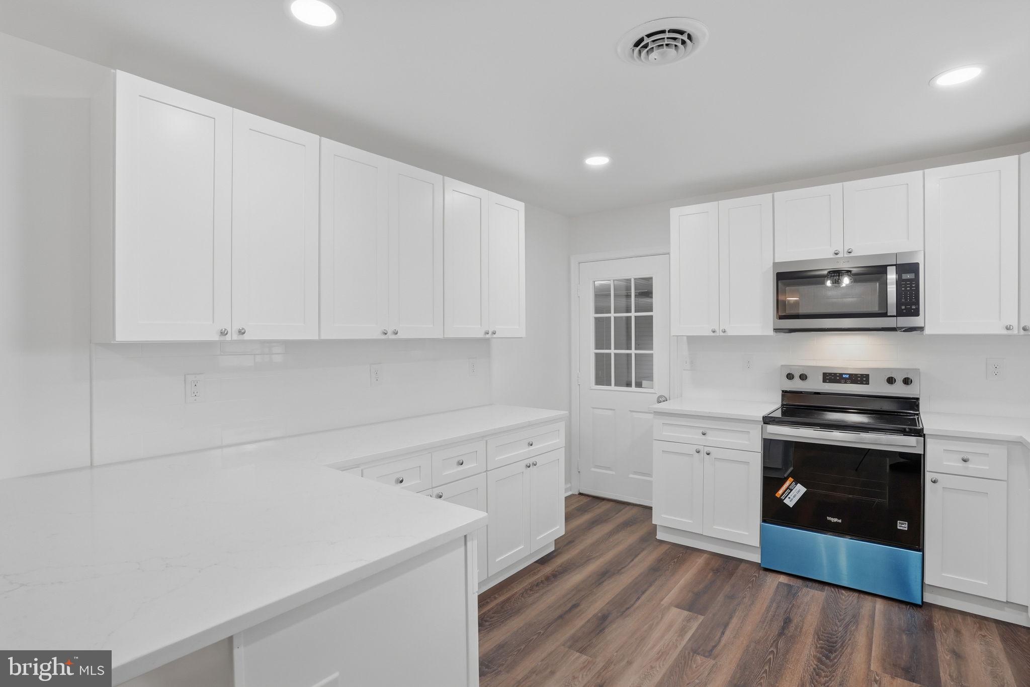 1804 Hourglass Road Hartly, DE 19953 - Photo 14 of 46 a kitchen with stainless steel appliances a stove top oven a sink a refrigerator white cabinets and wooden floor