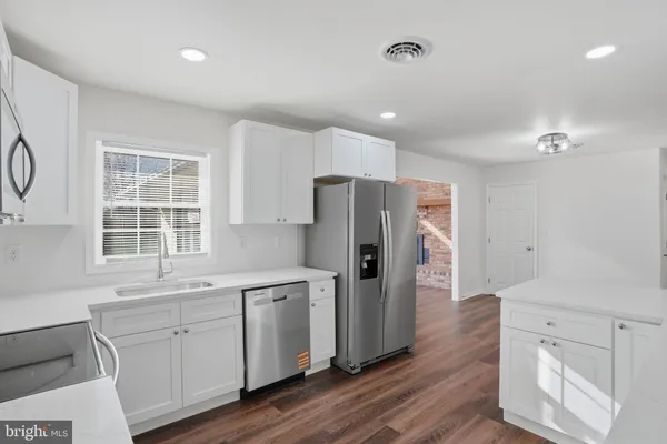 a kitchen with white cabinets and refrigerator