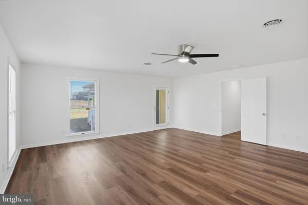 an empty room with wooden floor chandelier fan and windows