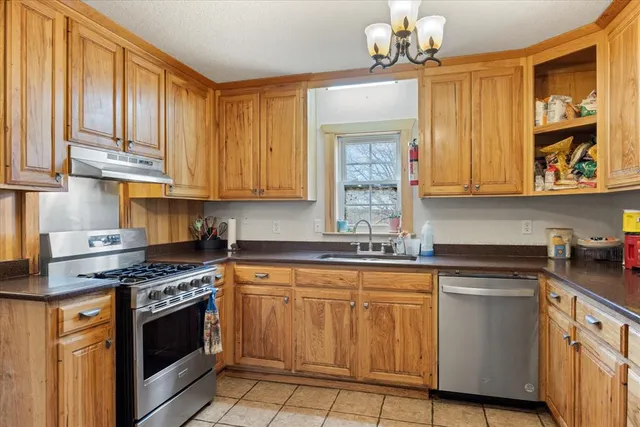 a kitchen with stainless steel appliances granite countertop a stove a sink dishwasher and cabinets with wooden floor