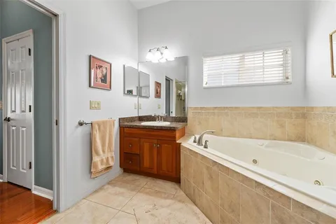 a spacious bathroom with a tub a sink and mirror