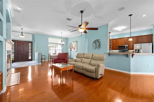 a living room with furniture kitchen view and a wooden floor
