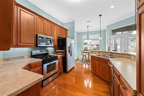 a kitchen with stainless steel appliances granite countertop a stove top oven a sink dishwasher a refrigerator and a cabinets with wooden floor