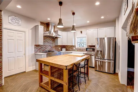 a kitchen with stainless steel appliances kitchen island a wooden floor and white cabinets